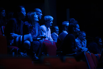 Fototapeta na wymiar Smiling, enthusiastic audience in dark auditorium