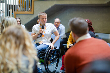 Audience watching male speaker in wheelchair talking on stage