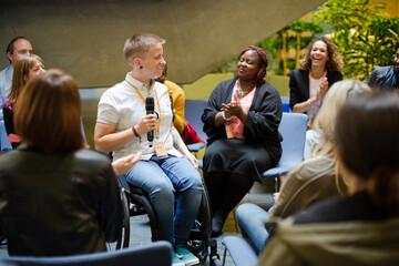 Audience watching male speaker in wheelchair talking on stage