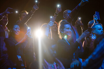 Excited audience with smart phone flashlights cheering