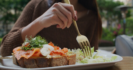 Woman eat salmon toast at outdoor cafe