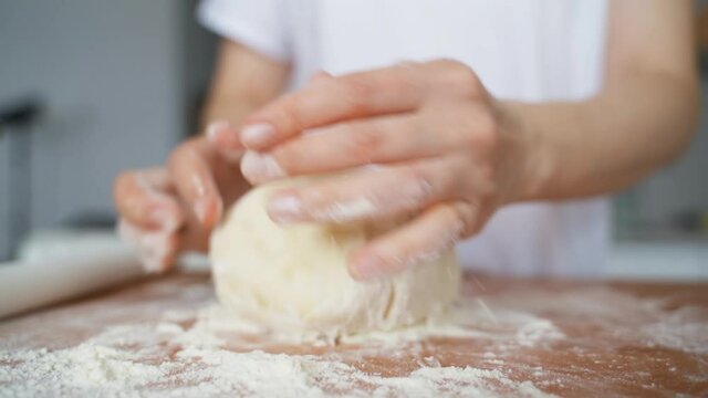 Female hands in the kitchen sculpt dough for baking.