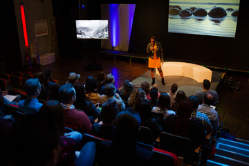 Female speaker on stage talking to audience