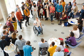 Obraz premium Audience watching male speaker in wheelchair talking on stage