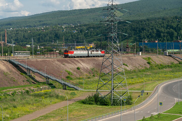 Electric locomotive on railway tracks against the background of mountainous terrain.