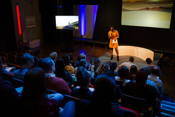 Female speaker on stage talking to audience