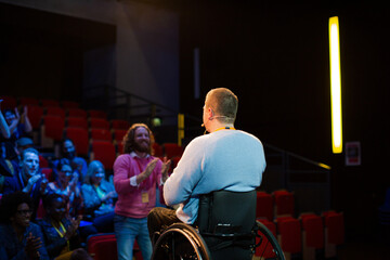 Speaker in wheelchair on stage talking to conference audience