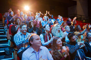 Happy audience clapping in dark room