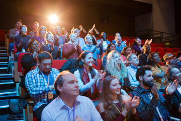 Happy audience clapping in dark room