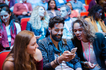 Man and woman with smart phone in conference audience