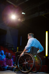 Speaker in wheelchair on stage talking to conference audience