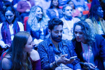 Man and woman with with smart phone in conference audience