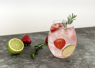 Strawberry and rosemary pink gin cocktail, refreshing alcohol drink with ice and lime. copy space.