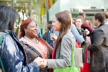 Three women greeting outside auditorium