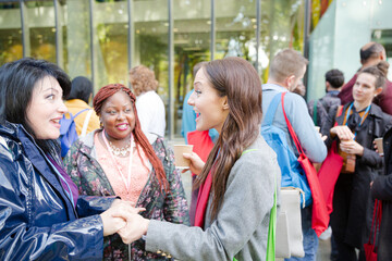 Three women greeting outside auditorium