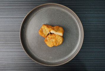 deep fried golden chicken nugget fritter with sauce on dark grey wood background dim sum halal menu