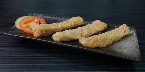 deep fried golden long fish paste wrapped in beancurd skin lobar wuxiang on dark grey wood background dim sum halal menu