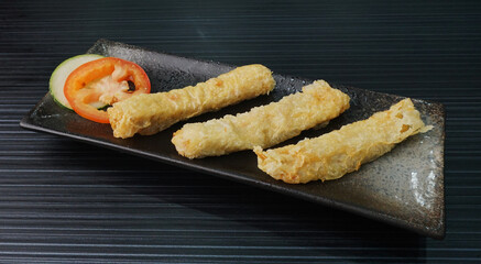 deep fried golden long fish paste wrapped in beancurd skin lobar wuxiang on dark grey wood background dim sum halal menu
