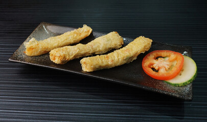 deep fried golden long fish paste wrapped in beancurd skin lobar wuxiang on dark grey wood background dim sum halal menu