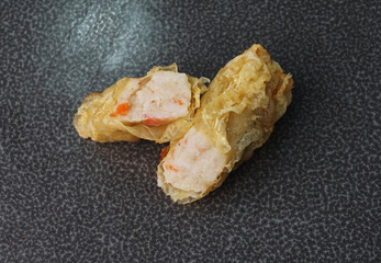 deep fried golden long fish paste wrapped in beancurd skin lobar wuxiang on dark grey wood...