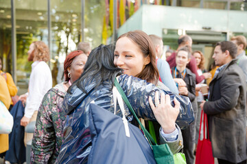 Three women greeting outside auditorium