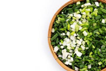 Chopped spring onions in bamboo basket on white background.