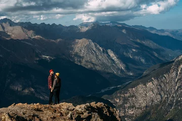 Fotobehang A couple in love on a rock admires the beautiful views. A man and a woman on a rock. A couple in love travels. A man and a woman in the Caucasus mountains. Couple traveling through the mountains © MISHA