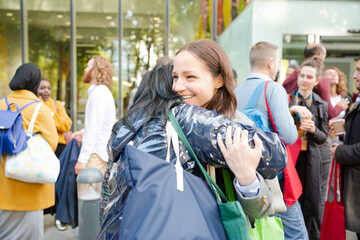 Three women greeting outside auditorium