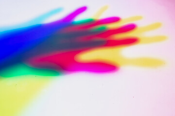 A blurred background with a shadow from the palm of the hand of yellow, red, blue color from three multi-colored light sources