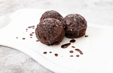 Chocolate muffins on a white plate. Sprinkled with chocolate and coconut on top. Homemade fluffy and juicy chocolate cakes. On a gray background