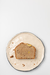 A piece of banana bread on a white plate on a light background