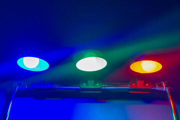 Green, red, blue colors from three multi-colored light sources shine in the dark