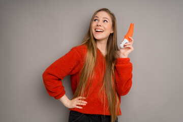 An Italian girl in a red sweater is holding a red vibrator or a dildo for sex.Useful for a sex shop