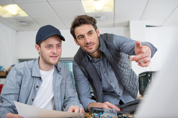 tutor giving instructions to apprentice engineer