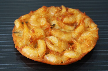 deep fried crispy golden fresh prawn fritter pan cake in round shape on dark grey wood background asian dim sum halal food restaurant cuisine banquet menu for cafe