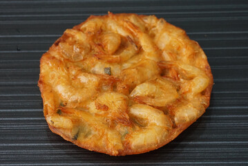 deep fried crispy golden fresh prawn fritter pan cake in round shape on dark grey wood background dim sum halal menu