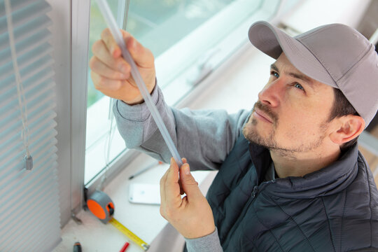 construction worker man install blinds on plastic windows in house