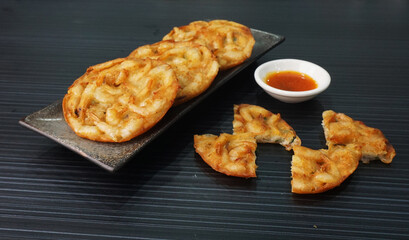 deep fried crispy golden fresh prawn fritter pan cake in round shape on dark grey wood background dim sum halal menu