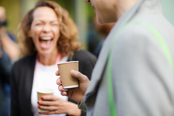 People holding coffee cups during conference break