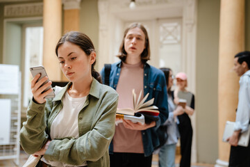 Young european students standing in line at library