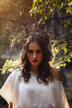 Beautiful mystery gothic woman in long white dress in autumn forest.