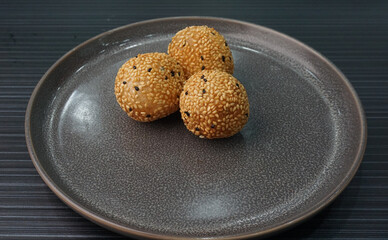 deep fried golden crispy sesame ball wrapped with sweet pandan lotus paste lava dessert on dark...