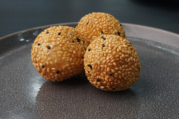 deep fried golden crispy sesame ball wrapped with sweet pandan lotus paste lava dessert on dark...