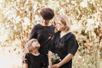 mother with two girls daughters in nature in the summer walk. Mom throw their children