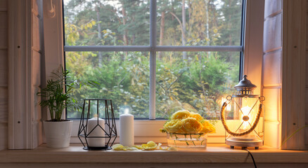 Yellow roses on windowsill, candles, autumn leaves, lantern.