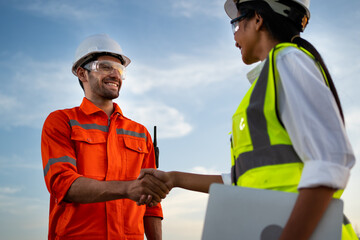 Engineers join hands to congratulate the success of the plant's operations. Engineer inspecting in...