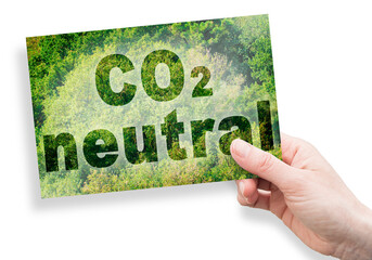 CO2 Neutral text - concept against a forest backgound and hand holding a postcard
