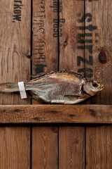 Sun-dried roach with paper label on tail on rough wooden boards