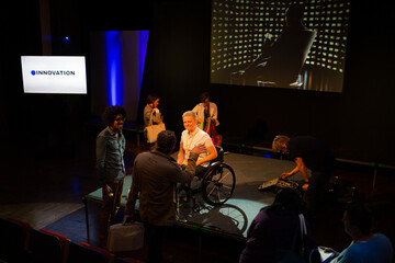 Speaker in wheelchair on stage talking to conference audience