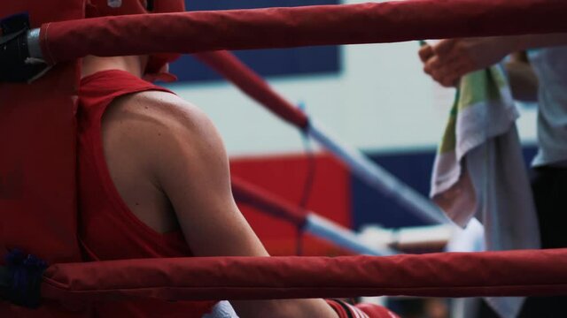 Boxing tournament. The athlete is resting between rounds. Coach giving instructions. Fighter in the boxing ring, listening to the fight strategy. The concept of professional sports and defence